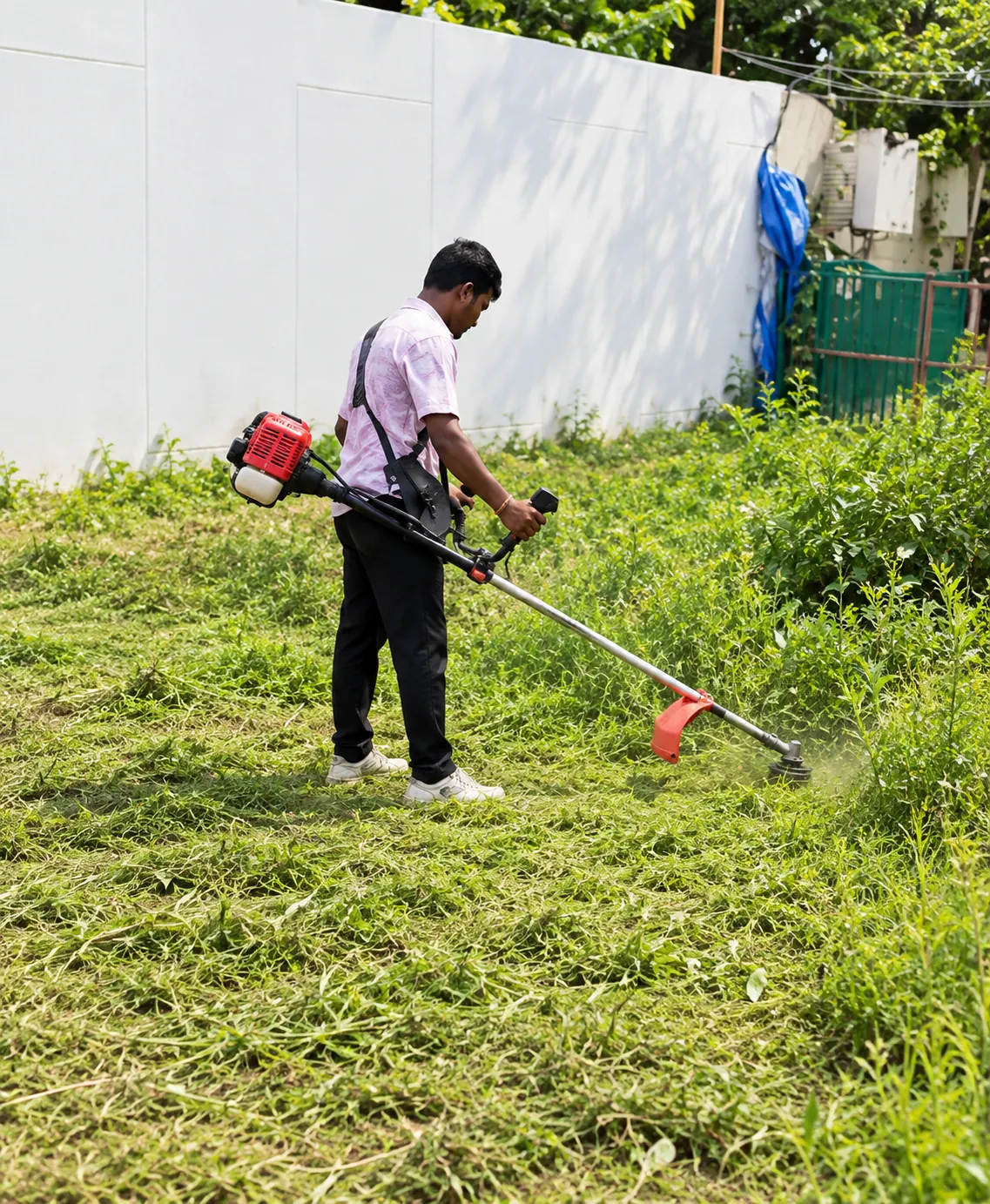 Worker brush cutting weeds on a vacant site in Bangalore